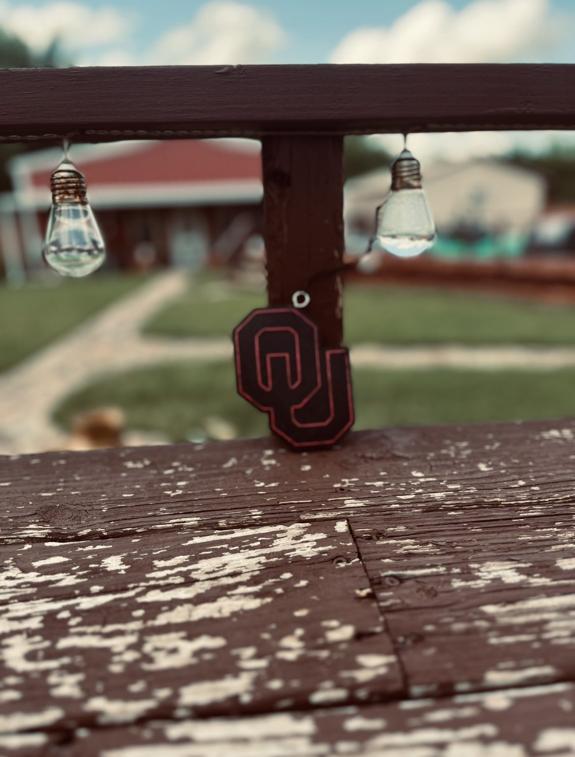 Keychains hanging on a wooden railing with a blurred outdoor background.