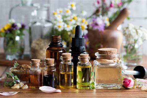 Various essential oil bottles and crystals on a wooden surface with flowers in the background.