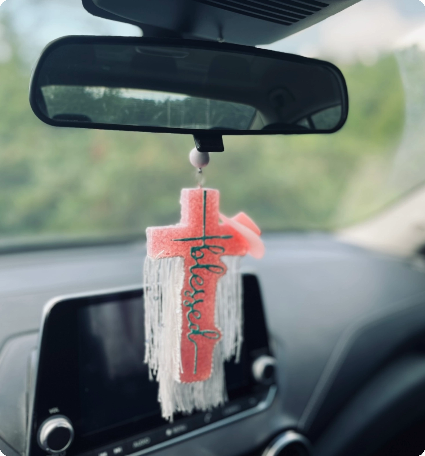 Car rearview mirror with a hanging red and white tassel charm.
