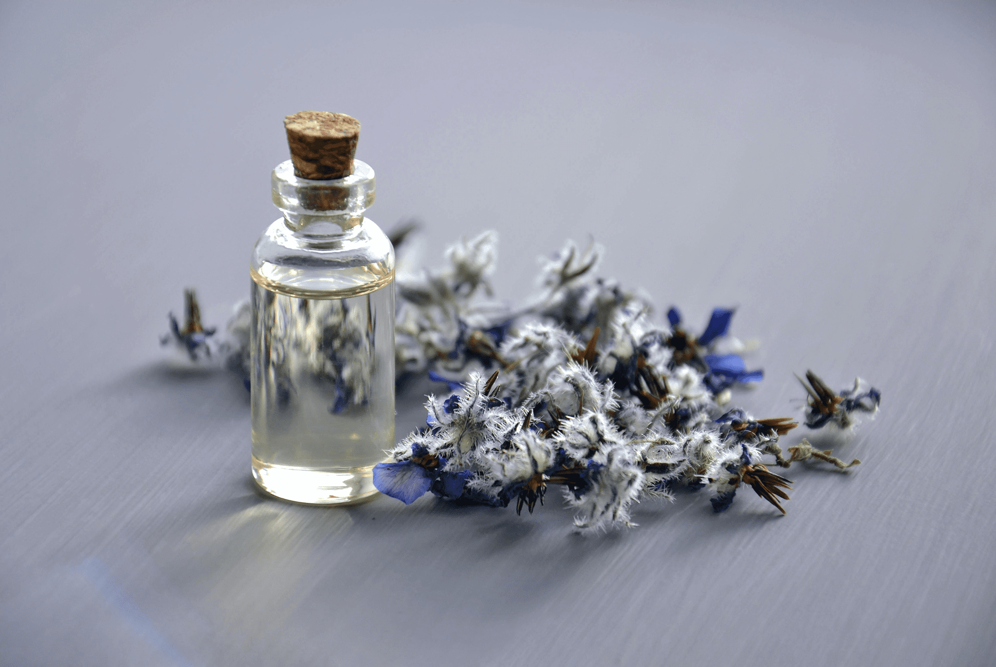 A small glass bottle with cork and dried lavender flowers.